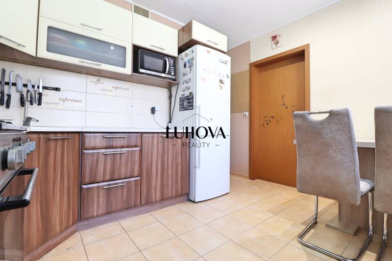 Kitchen in a 3-room apartment with wooden cabinets, appliances, and a dining table.