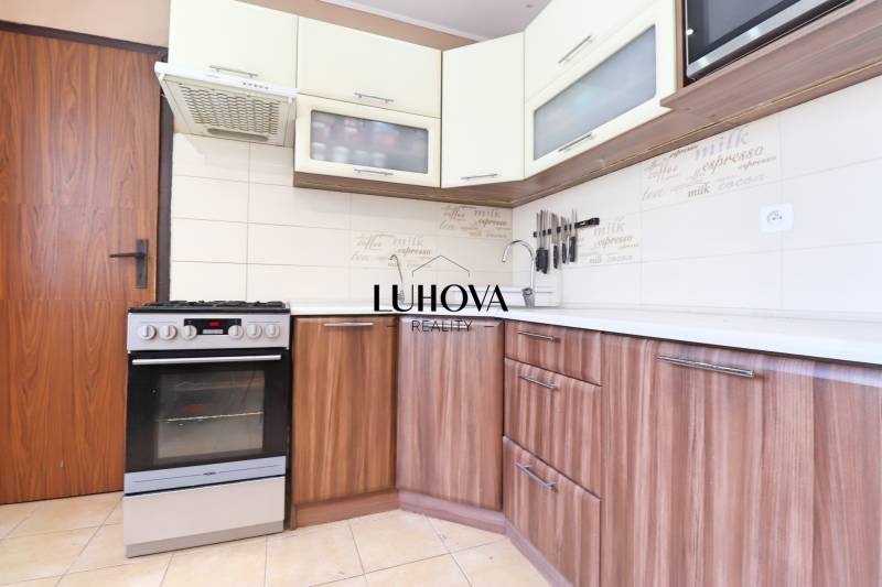 A kitchen in a 3-room apartment with a stove and wooden cabinets, light tiles.