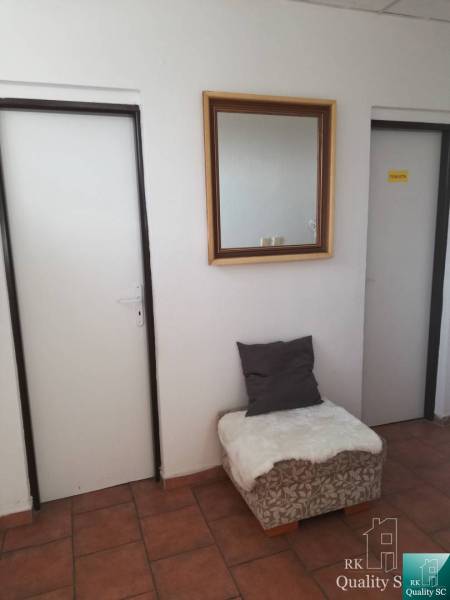 Interior of a building with a hallway, mirror, doors, and a seat with a cushion.