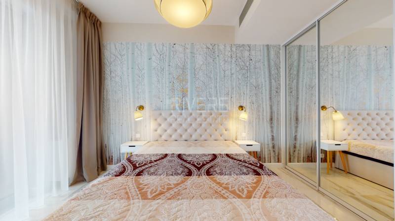 A bedroom with a patterned curtain, a mirrored wardrobe, and a lamp in a two-room apartment.