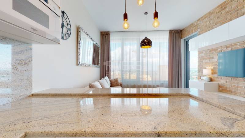 A kitchen countertop made of granite stone in a 2-room apartment with a brick wall and lighting.