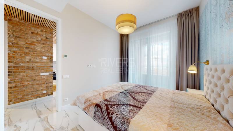 A bedroom in a two-room apartment with a brick wall and a curtain.