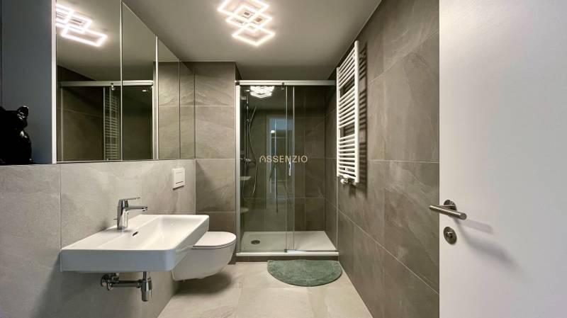 Bathroom with a shower, sink, and mirror in a 2-room apartment.
