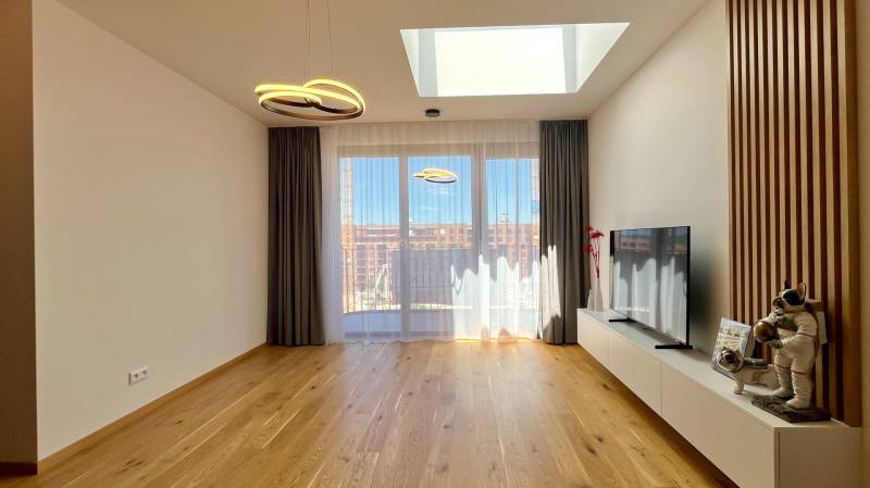 Living room in a two-room apartment with a TV and decorations on the floor.