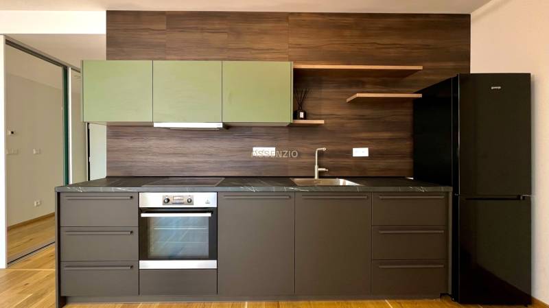 A kitchen in a 2-room apartment with dark furniture and built-in appliances.
