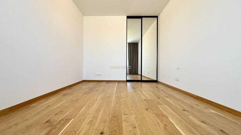 A room with a wooden floor and a mirrored wardrobe in a 2-room apartment.