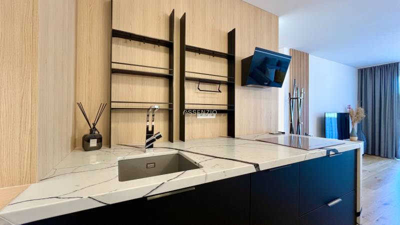A kitchen unit with a marble countertop and open shelves in a two-room apartment.