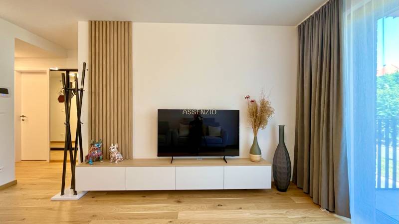 A bright living room in a 2-room apartment with a TV and decorations.