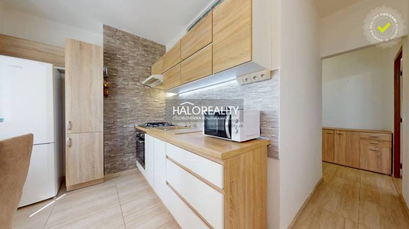 A kitchen in a 3-room apartment with wooden furniture and brick wall cladding, appliances.