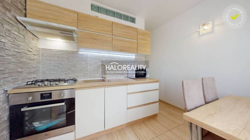A kitchen in a 3-room apartment with wooden cabinets and a dining table.