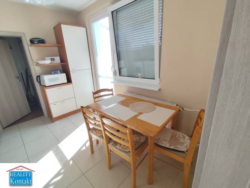 Dining table with chairs in the kitchen of a 3-room apartment, next to a kitchen cabinet.