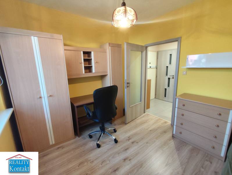 A room with furniture in a 3-room apartment, wooden floor, yellow walls, desk, chair.