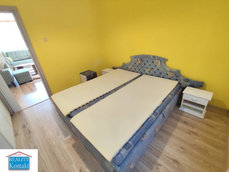 Bedroom in a 3-room apartment with a yellow wall, bed, and nightstands.