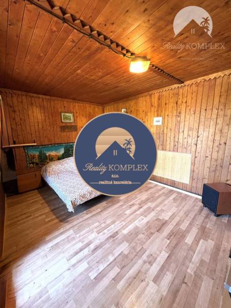 Wooden interior of a cabin with a bed and wooden floor.