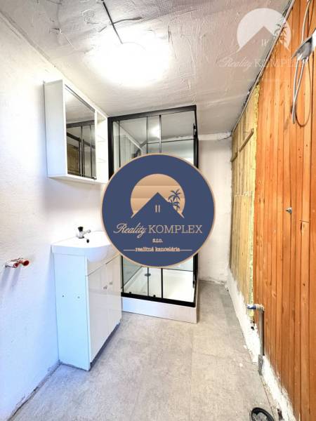 A bathroom in a cabin with a sink and a shower, wooden and white wall.