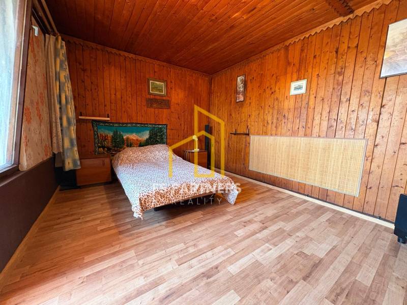 A wooden interior with a patterned bed and paintings on the walls.