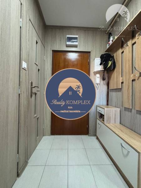 A hallway in a one-room apartment with built-in furniture and tiled flooring.