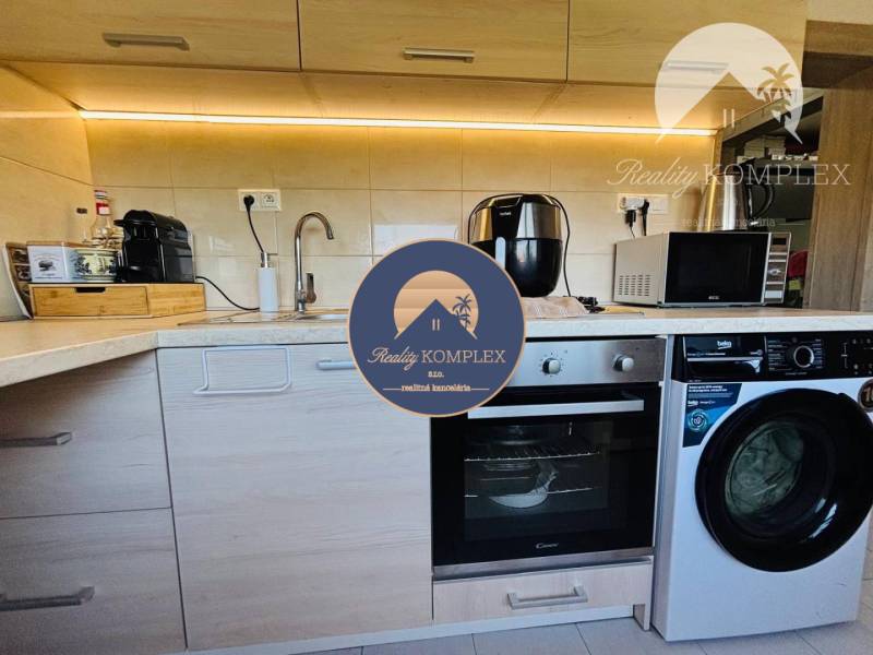 Kitchen in a studio apartment with a cooktop, dishwasher, and washing machine.