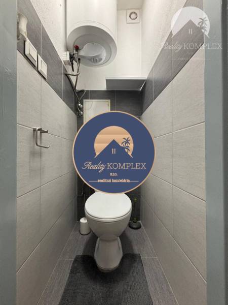 A bathroom in a one-room apartment with a wall-mounted heater, simple design, and storage space.