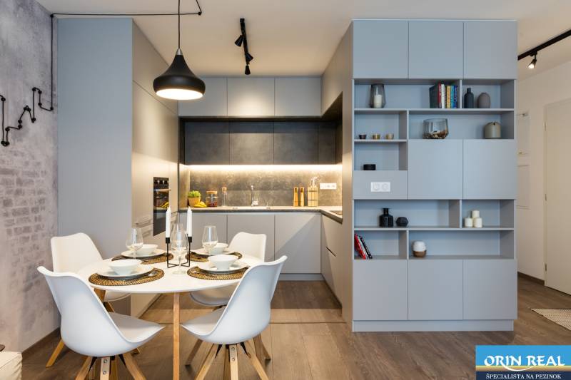 Dining room in a 2-room apartment with a modern table and chairs, gray kitchen cabinets.