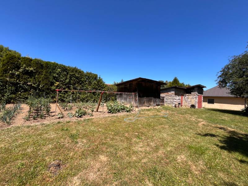 A garden with cultivation beds and a wooden shelter by a family house in Slovenská Kajňa.