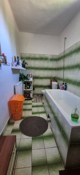 A bathroom in a family house with green and white tiles and an orange basket.