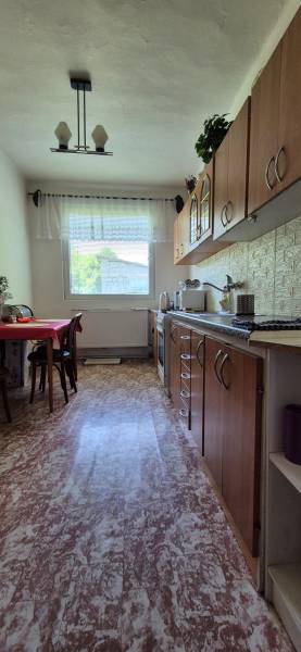 A kitchen in a family house with a wooden kitchen unit and a window that lets in daylight.