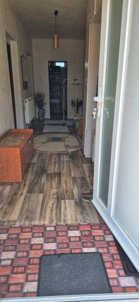 Entrance hallway of a family house with a wooden floor, shoe cabinet, and open doors.
