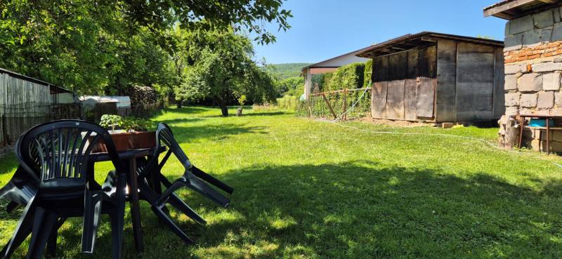 The garden of a family house in Slovenská Kajňa with plastic chairs and a wooden shelter.