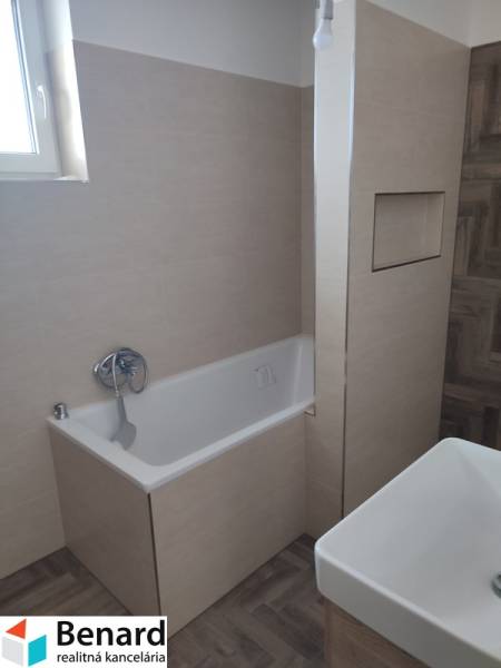 A bathroom in a family house with a bathtub, a sink, and tiles on the walls and floor.