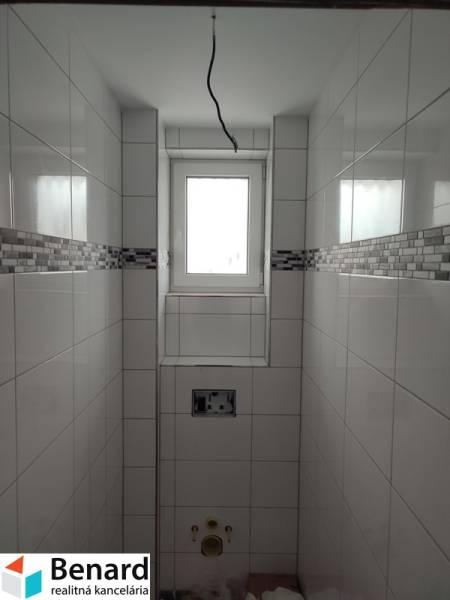 A bathroom in a family house with tiles and a window, without sanitary equipment.