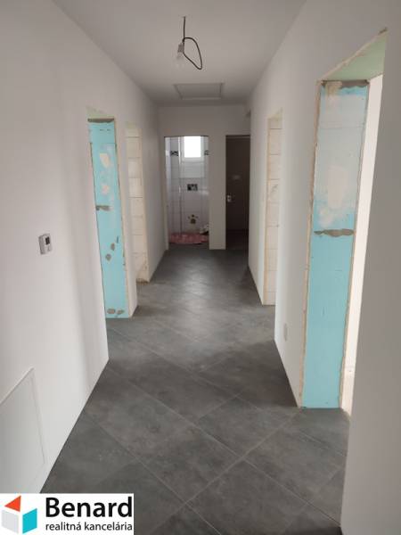 Hallway in a family house with tiles, white walls, and entrances to rooms.