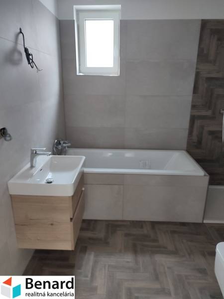 Bathroom in a family house with a bathtub, sink, and ceramic tiles.