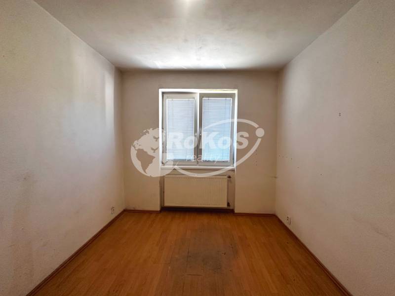 An empty room with a parquet floor and a window in a 3-room apartment.