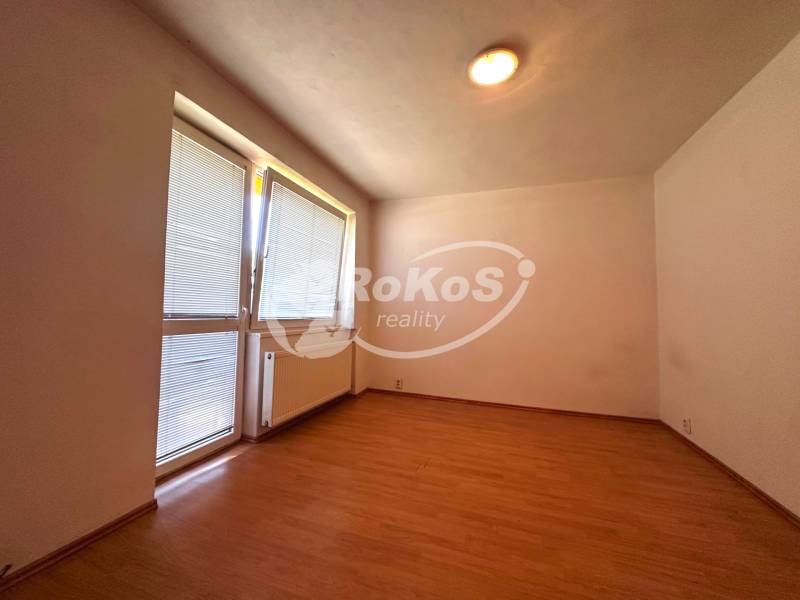 A room with a wooden floor, a radiator, and a window with blinds in a 3-room apartment.