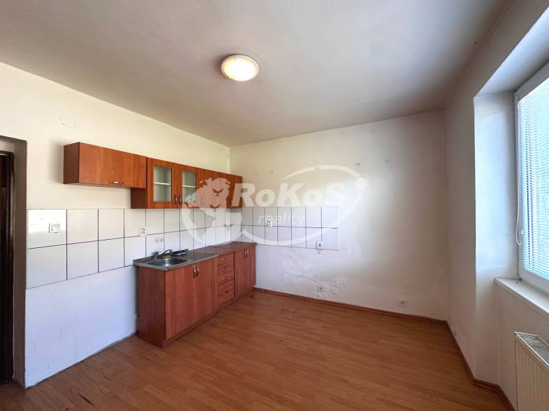 A kitchen in a 3-room apartment with a sink, tiles, and wooden flooring.