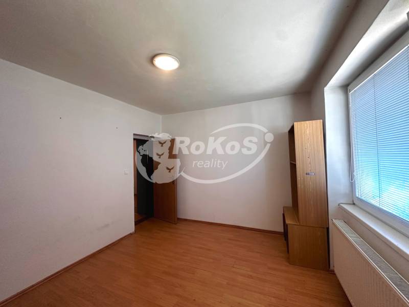 An empty room in a 3-room apartment with light furniture and a large window.