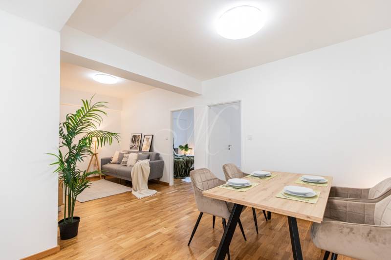 Dining table with four chairs, view into the living room in a three-room apartment.