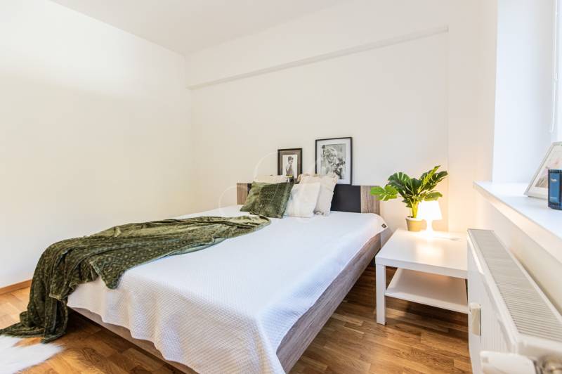 A bright bedroom with a large bed and a green throw in a 3-room apartment.