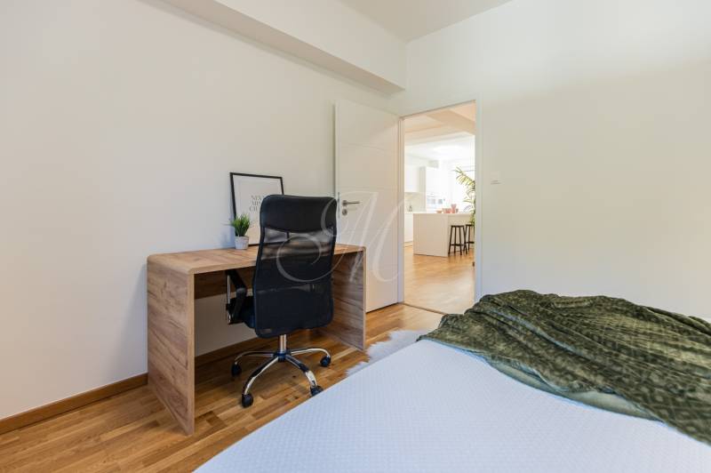 A workspace with a wooden desk and a black chair in a 3-room apartment.