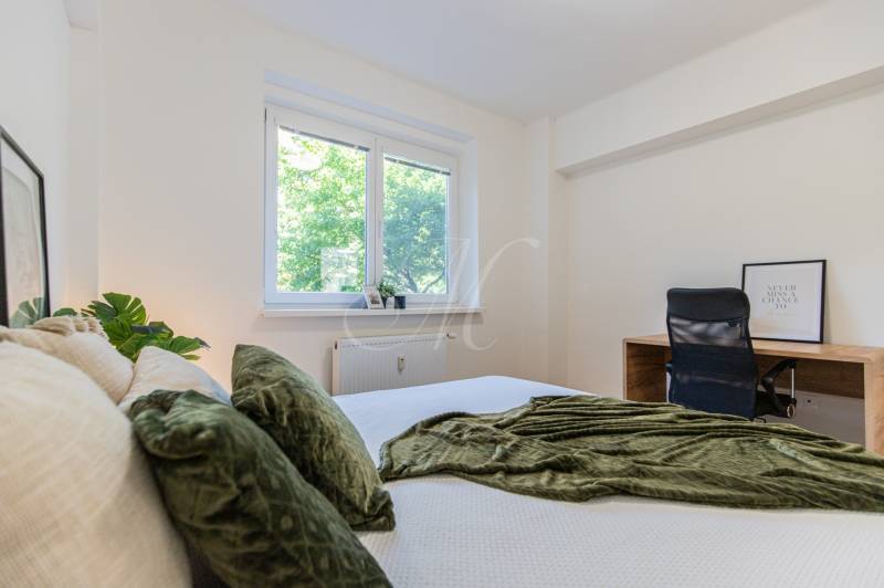 A bright bedroom with a bed and a desk in a 3-room apartment.