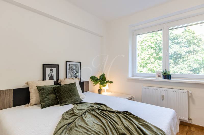 A bedroom with a window, a bed, and decorations in a 3-room apartment.
