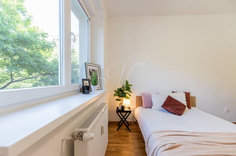 Bright bedroom in a 3-room apartment with a comfortable bed, decorations, and a large window.