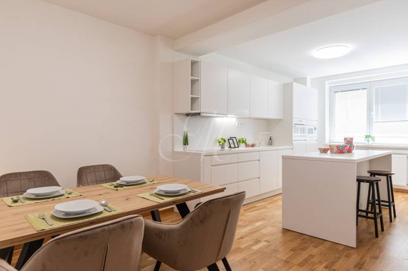 Dining table with place settings in the kitchen of a 3-room apartment with white furniture.