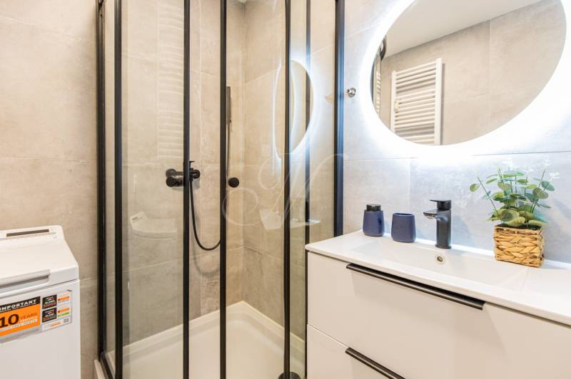 Bathroom with a shower, mirror, and washing machine in a 3-room apartment.