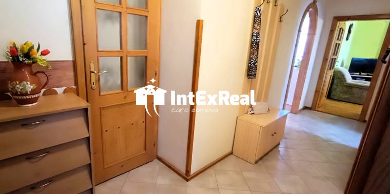 A hallway in a 3-room apartment with wooden furniture and decoration in a vase.