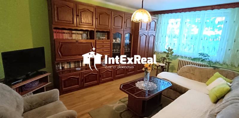 Living room with a sofa, display cabinet, and television in a three-room apartment.