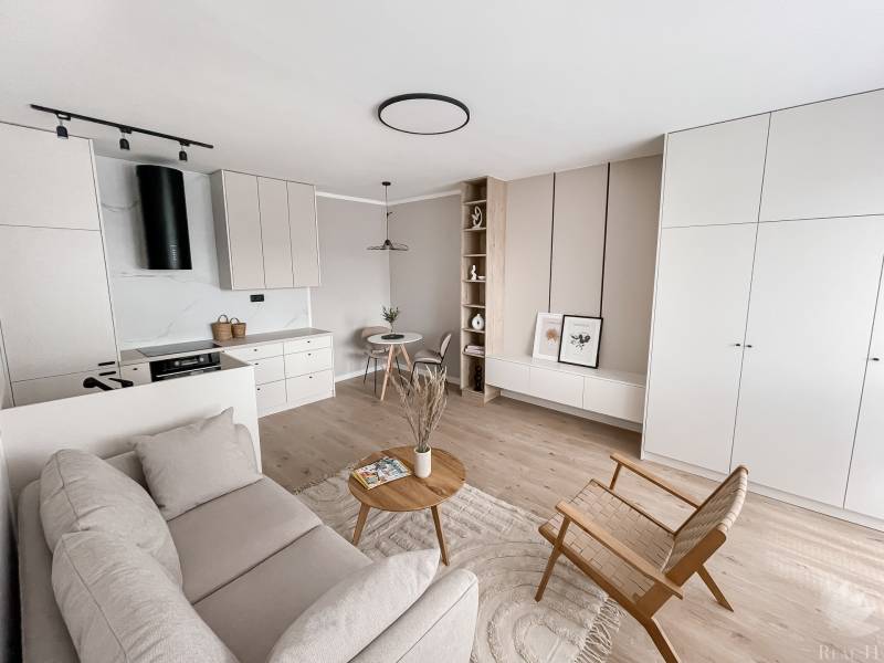 A bright interior with minimalist furniture, decorations, and wooden elements resembles a 2-room apartment.