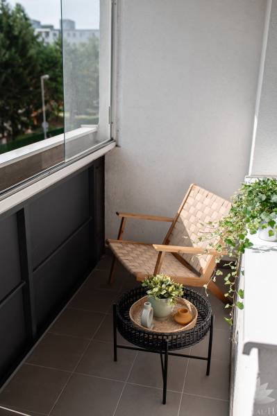 Balcony of a 2-room apartment with a chair, table, and plants.