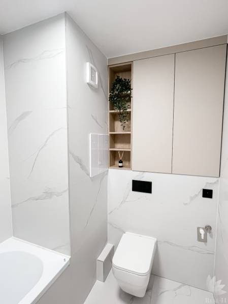 A minimalist bathroom in a 2-room apartment with a toilet, bathtub, and storage spaces.